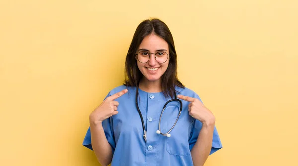 若いヒスパニック系の女性は幸せと興奮して自分自身を指して感じている 看護師の概念 — ストック写真