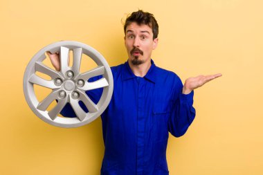 Adam şaşırmış ve şok olmuş görünüyor. Çenesi düşmüş ve elinde bir nesne tutuyor. araba tamircisi konsepti