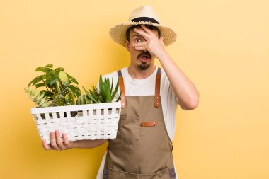 Adam şok olmuş, korkmuş ya da korkmuş görünüyor, yüzünü eliyle kapatıyor. Bahçıvan konsepti