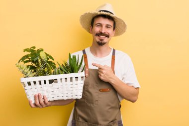 Neşeli bir şekilde gülümseyen, mutlu hisseden ve tarafını gösteren bir adam. Bahçıvan konsepti