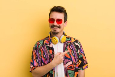 Neşeli bir şekilde gülümsüyor, mutlu hissediyor ve bir tarafı işaret ediyor. müzik konseptini dinlemek