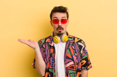 Şaşırmış ve şok olmuş bir şekilde, çenesi düşmüş bir şekilde elinde bir nesne tutarken. müzik konseptini dinlemek