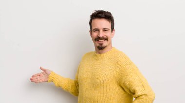 İspanyol genç adam kendini mutlu ve neşeli hissediyor, gülümsüyor ve seni hoş karşılıyor, dostça bir jestle içeri davet ediyor.