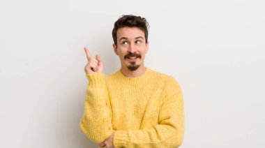 İspanyol genç adam mutlu bir şekilde gülümsüyor ve yan bakıyor, merak ediyor, düşünüyor ya da bir fikri var.