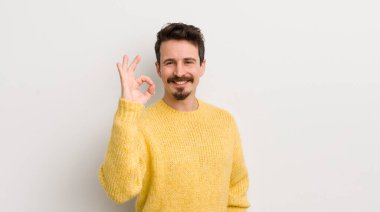 İspanyol genç adam kendini mutlu, rahat ve tatmin olmuş hissediyor. Onayını iyi bir hareketle gösteriyor. Gülümsüyor.