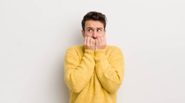 İspanyol genç adam endişeli, gergin, stresli ve korkmuş görünüyor, tırnak yiyor ve yanal fotokopi alanı arıyor.