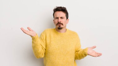 İspanyol genç adam şaşkın, şaşkın ve stresli görünüyor, farklı seçenekler arasında merak ediyor, kararsız hissediyor