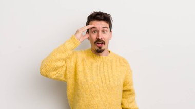 İspanyol genç adam mutlu, şaşkın ve şaşırmış görünüyor, gülümsüyor ve inanılmaz ve inanılmaz iyi haberleri fark ediyor.