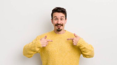 İspanyol genç adam mutlu, şaşkın ve gururlu hissediyor, heyecanlı, şaşkın bakışlarıyla kendini işaret ediyor.