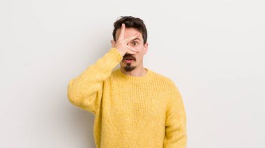 İspanyol genç adam şok olmuş, korkmuş ya da korkmuş görünüyor. Yüzü elle kaplanmış ve parmaklarının arasından gizlice bakıyor.