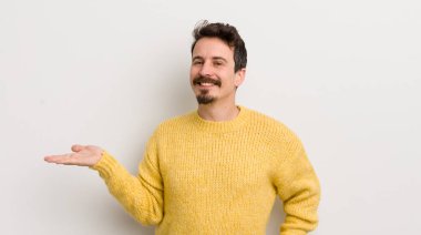 İspanyol genç adam gülümsüyor, kendinden emin, başarılı ve mutlu hissediyor, fotokopi alanında fikir veya konsept gösteriyor.