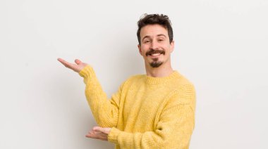 İspanyol genç adam gururla ve kendinden emin bir şekilde gülümsüyor, mutlu ve tatmin olmuş hissediyor ve fotokopi alanında bir konsept gösteriyor.