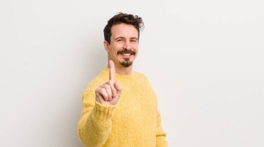 İspanyol asıllı genç adam gururla gülümsüyor ve gururla bir numaralı pozu veriyor, kendini lider gibi hissediyor.