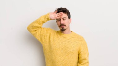 İspanyol genç adam stresli, yorgun ve hayal kırıklığına uğramış görünüyor, alnından ter damlıyor, umutsuz ve bitkin hissediyor.