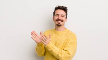 İspanyol genç adam mutlu ve başarılı hissediyor, gülümsüyor ve alkışlıyor, alkışlarla tebrik ediyor.