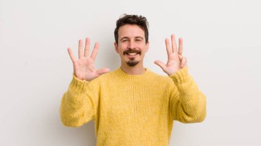 İspanyol genç adam gülümsüyor ve arkadaş canlısı görünüyor, 9 ya da 9 numarayı gösteriyor, eli önde, geri sayıyor.