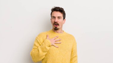 İspanyol genç adam şaşkın, şaşkın ve şaşırmış hissediyor, elleri göğsünde ve ağzı açık, kim olduğunu söylüyor, ben?