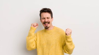 İspanyol genç adam son derece mutlu ve şaşırmış görünüyor, başarıyı kutluyor, bağırıyor ve zıplıyor.