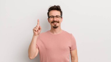 İspanyol genç adam mutlu bir şekilde gülümsüyor, tek eliyle uzayı işaret ediyor.