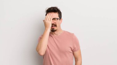 İspanyol genç adam uykulu görünüyor, sıkılmış ve esniyor, baş ağrısı ve yüzünün yarısını kaplayan bir elle.