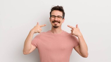 İspanyol genç adam kendine güvenerek gülümsüyor. Geniş gülümseme, pozitif, rahat, tatmin olmuş tavır.