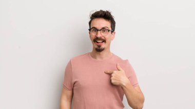 İspanyol genç adam mutlu, gururlu ve şaşırmış görünüyor, neşeli bir şekilde kendini gösteriyor, kendinden emin ve kibirli hissediyor.