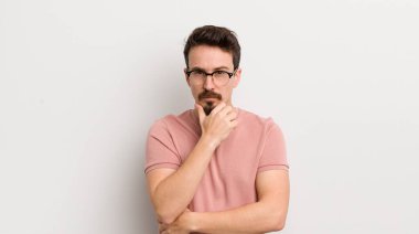 Hispanik genç adam ciddi görünüyor, kafası karışık, kararsız ve düşünceli, seçenekler veya seçimler arasında şüpheci