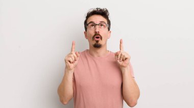 Hispanik genç adam şaşırmış ve ağzı açık. Şok olmuş ve şaşırmış bir bakışla yukarı bakıyor.