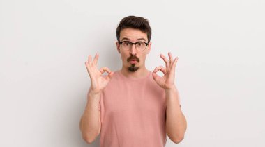 İspanyol genç adam şok olmuş, şaşırmış ve şaşırmış hissediyor. Onayladığını gösteriyor. İki eliyle işaret veriyor.