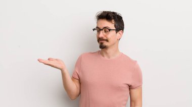 İspanyol genç adam kendini mutlu hissediyor ve gülümsüyor. Yanında duran bir nesneye ya da konsepte bakıyor.