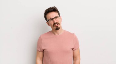 hispanic young man feeling puzzled and confused, with a dumb, stunned expression looking at something unexpected