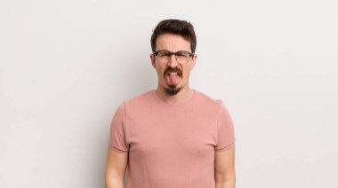 İspanyol genç adam tiksinti ve tedirginlik duyuyor, dilini dışarı çıkarıyor, iğrenç ve iğrenç bir şeyden hoşlanmıyor.