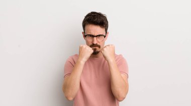 İspanyol genç adam kendinden emin, sinirli, güçlü ve agresif görünüyor. Yumrukları boks pozisyonunda dövüşmeye hazır.