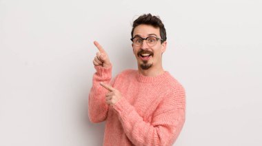 İspanyol genç adam sevinçli ve şaşırmış hissediyor, şok olmuş bir ifadeyle gülümsüyor ve yüzünü işaret ediyor.