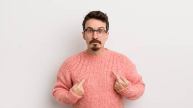 İspanyol genç adam şaşkın ve şaşkın bir bakışla kendini işaret ediyor. Seçildiğine şaşırmış ve şaşırmış.