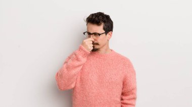 İspanyol genç adam iğreniyor, pis ve nahoş bir kokuyu koklamamak için burnunu tutuyor.