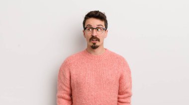 İspanyol genç adam şaşkın, mutlu, şaşkın ve şaşırmış hissediyor, ağzı açık bir şekilde yana bakıyor.