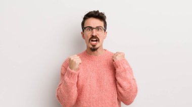 Öfkeli bir ifadeyle saldırganca bağıran İspanyol genç adam ya da başarıyı kutlayan yumruklar.