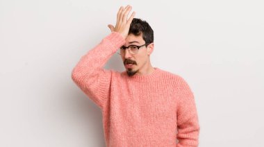 hispanic young man raising palm to forehead thinking oops, after making a stupid mistake or remembering, feeling dumb