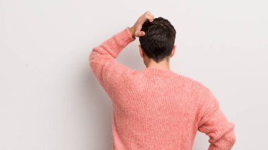 İspanyol genç adam bilgisiz ve kafası karışık hissediyor, bir çözüm düşünüyor, eli kalçasında, diğeri kafasında, dikiz aynasından.