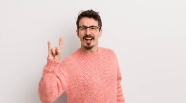 İspanyol genç adam kendini mutlu, eğlenceli, kendinden emin, pozitif ve asi hissediyor, elle rock veya heavy metal işareti yapıyor.