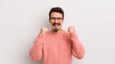 İspanyol genç adam mutlu, pozitif ve başarılı hissediyor, zaferi, başarıları veya iyi şansı kutluyor.