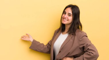 Genç İspanyol kadın kendini mutlu ve neşeli hissediyor, gülümsüyor ve seni hoş karşılıyor, seni dostça bir jestle içeri davet ediyor.