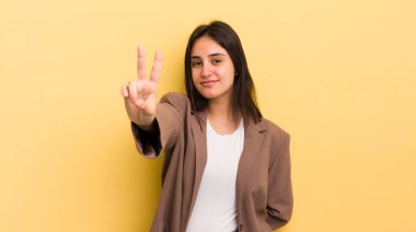 Genç İspanyol kadın gülümsüyor ve mutlu görünüyor, kaygısız ve pozitif, zafer ya da barışı simgeliyor.