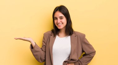 Genç İspanyol kadın gülümsüyor, kendinden emin, başarılı ve mutlu hissediyor, fotokopi alanında fikir veya konsept gösteriyor.