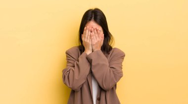 Genç İspanyol kadın üzgün, hayal kırıklığına uğramış, gergin ve depresif, iki eliyle yüzünü kaplayan, ağlayan