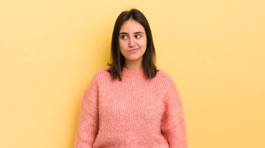 Genç İspanyol kadın şaşkın ve şaşkın görünüyor, merak ediyor veya bir sorunu çözmeye çalışıyor veya düşünüyor.