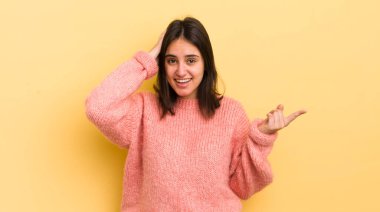 Genç İspanyol kadın gülüyor, mutlu, pozitif ve şaşırmış görünüyor. Yan fotokopi alanını işaret eden harika bir fikrin farkına varıyor.