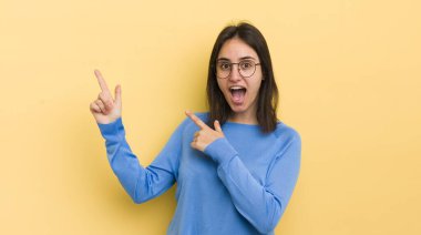 Genç İspanyol kadın sevinçli ve şaşırmış hissediyor. Şok olmuş bir ifadeyle gülümsüyor ve bir tarafı işaret ediyor.