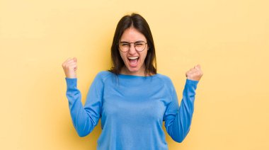 Genç İspanyol kadın öfkeli bir ifadeyle ya da yumruklarıyla saldırganca bağırıyor başarıyı kutluyor.